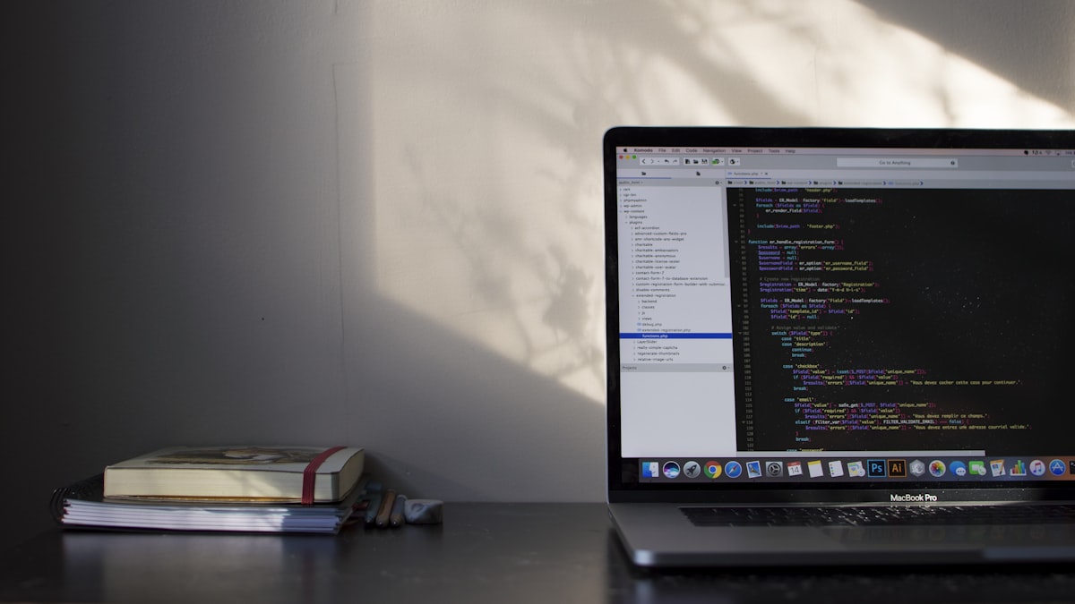 A laptop showing lines of code on a desk in low light