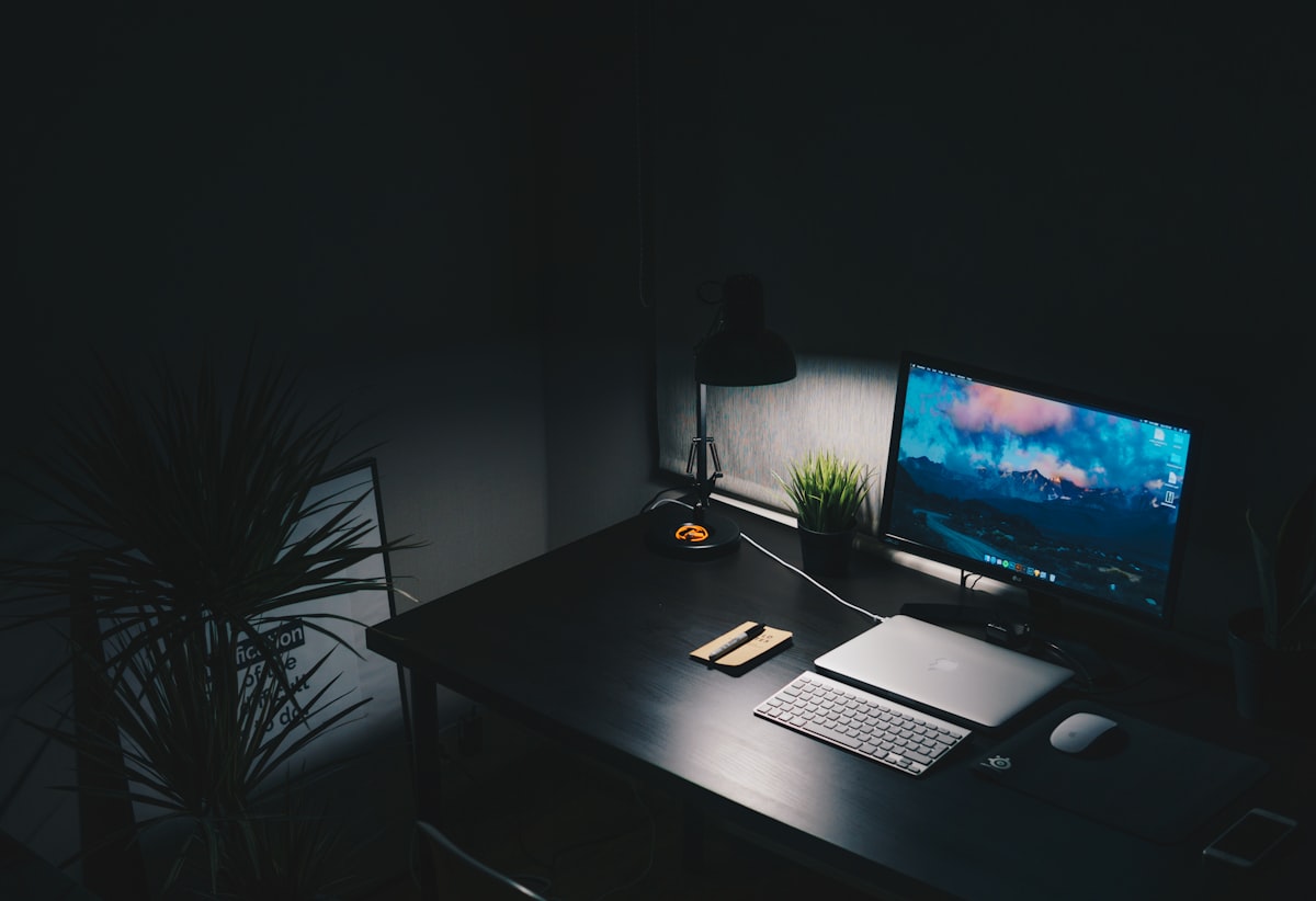 A dark desk workspace lit by a monitor at night